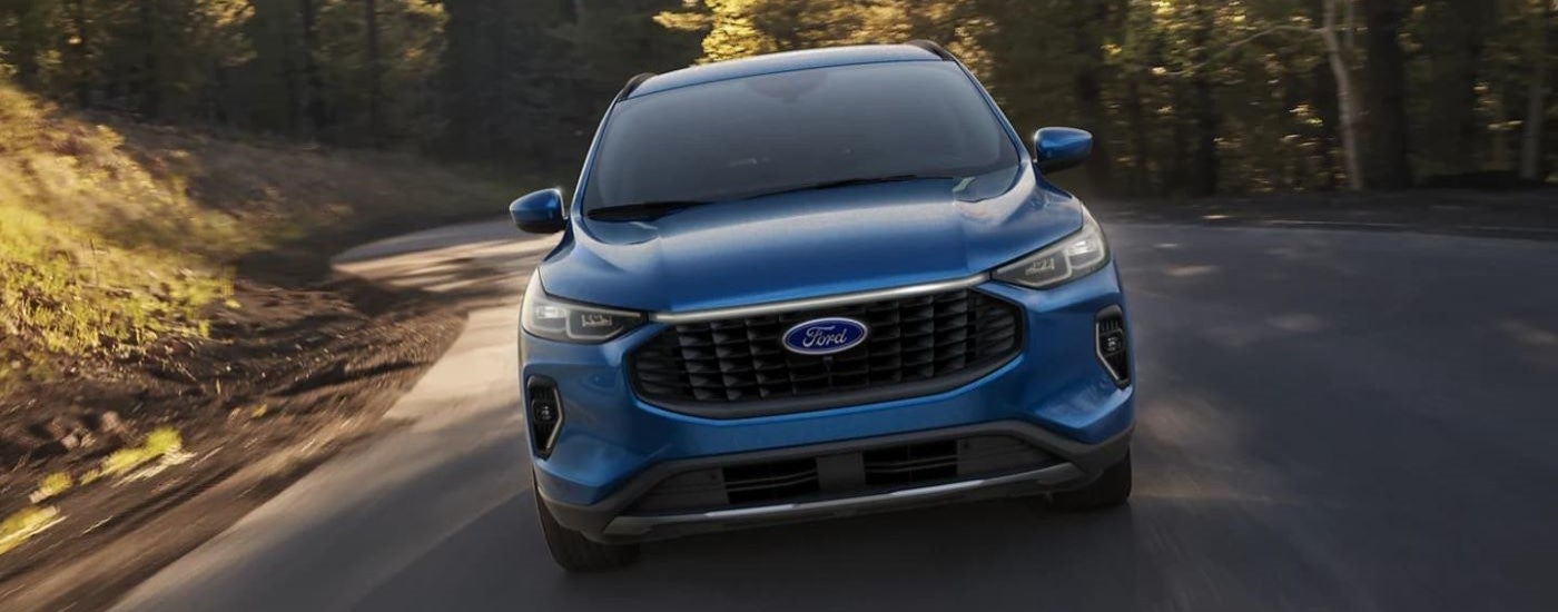 A blue 2023 Ford Escape driving down a rural road