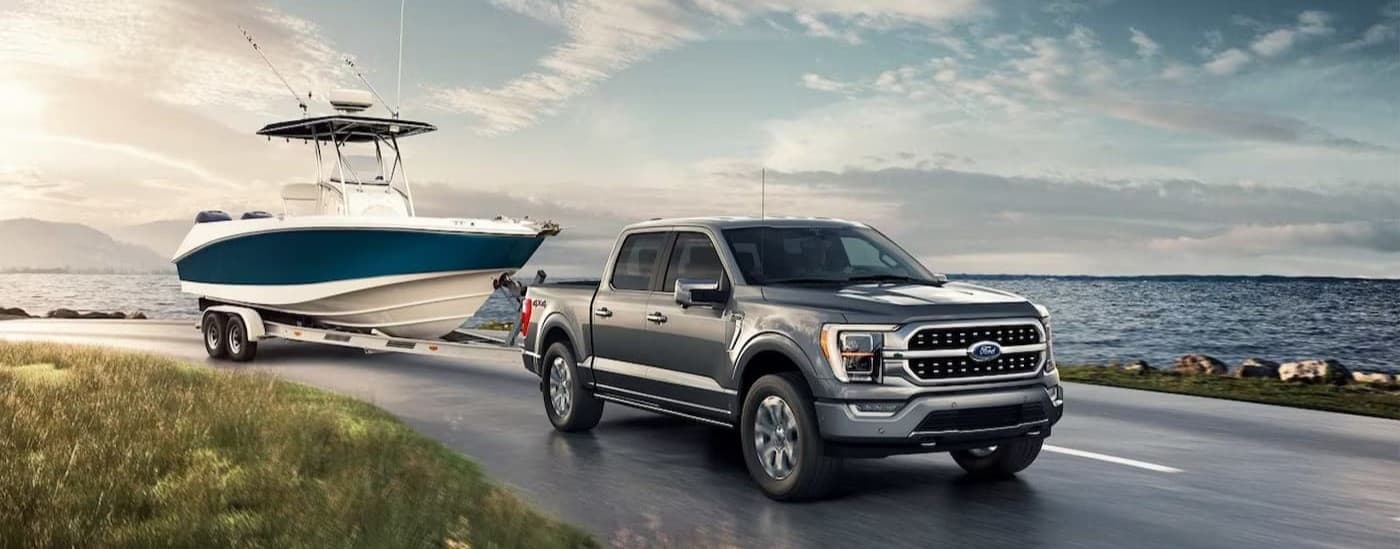 A silver 2024 Ford F-150 towing a boat.