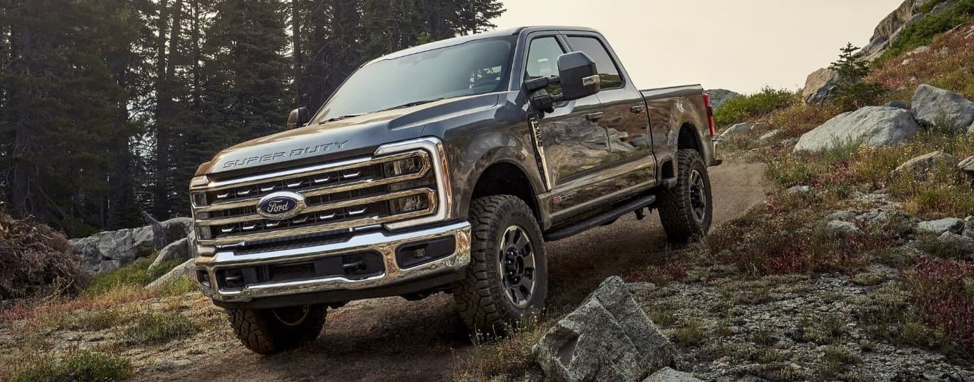 Grey 2026 Ford F-250 Tremor driving off-road down a hill.