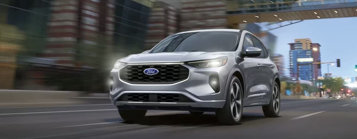 A silver 2024 Ford Escape driving in a city.
