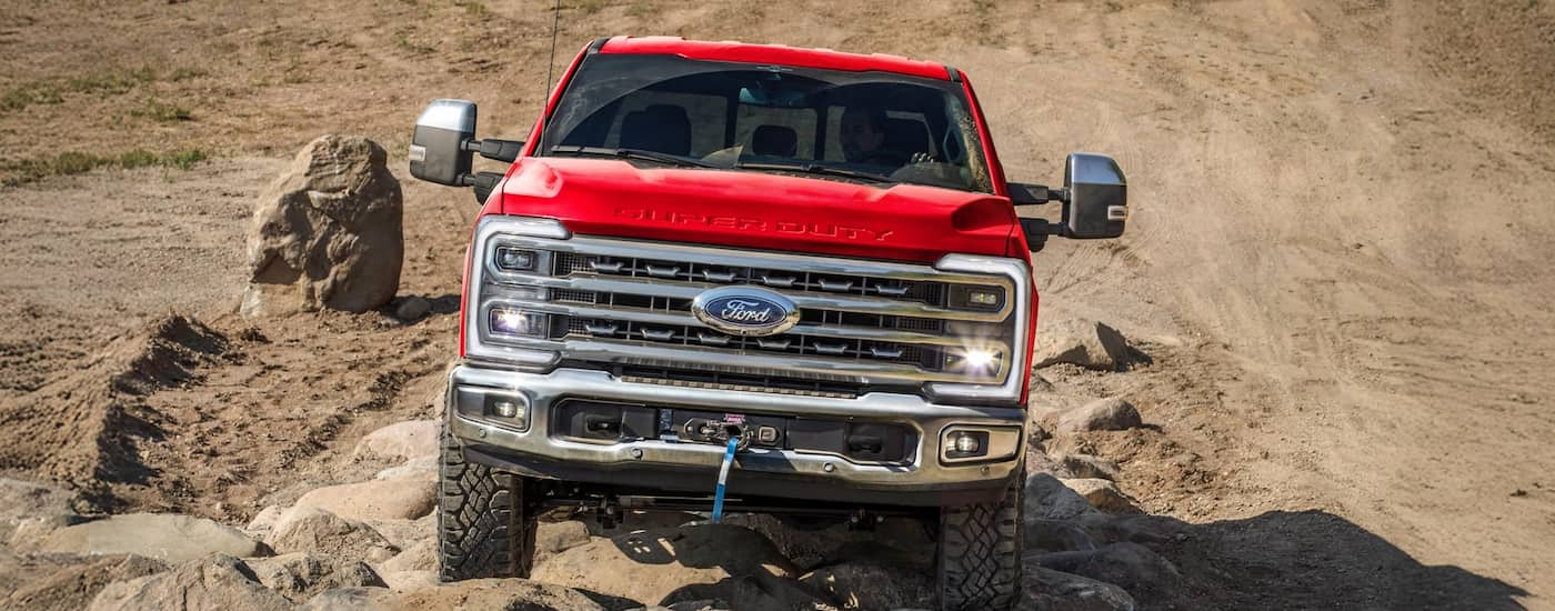 Front of a red 2026 Ford F-250 driving off-road.
