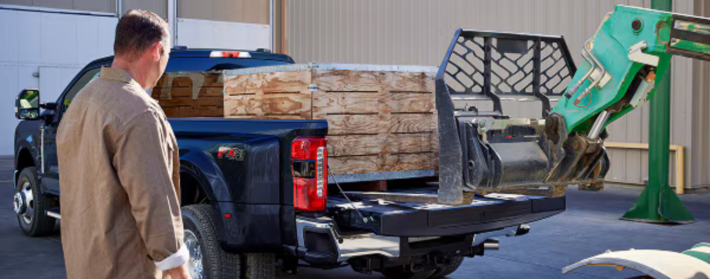 A crate being loaded into the bed of a blue 2026 Ford F-350