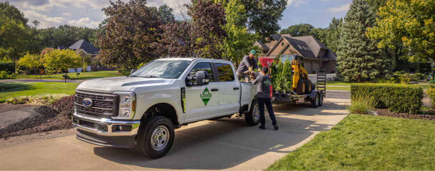 A landscaping crew unloading the bed of a white 2026 Ford F-350