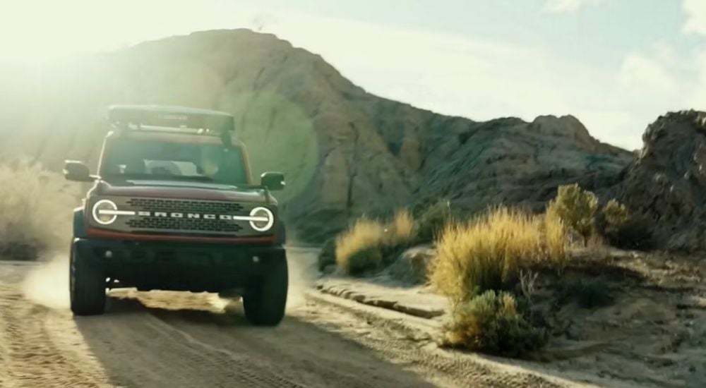 Red 2026 Ford Bronco driving off-road in the desert.