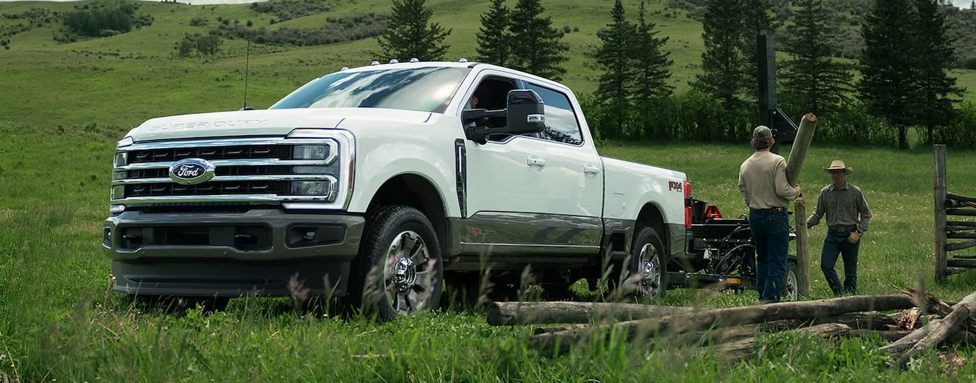 Workers loading logs into the bed of a white 2027 Ford F-250.