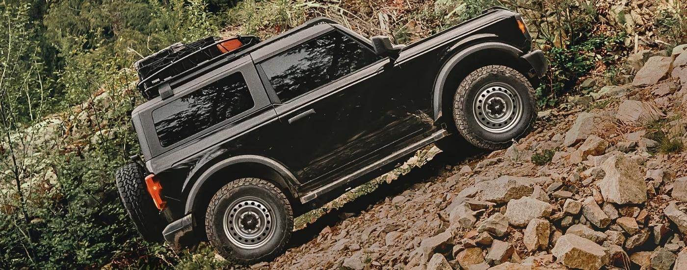 A black 2025 Ford Bronco driving up a hill.