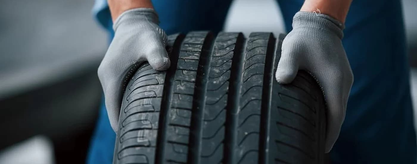 Close-up on a tire being rolled by a mechanic.
