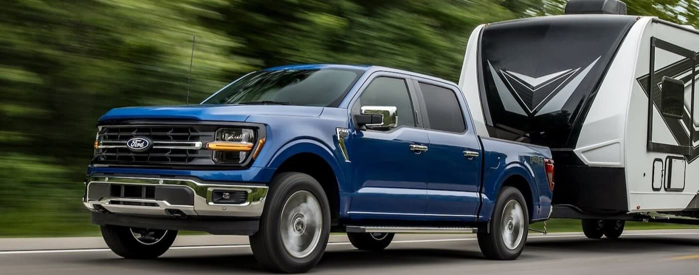 A blue 2024 Ford F-150 towing a trailer.